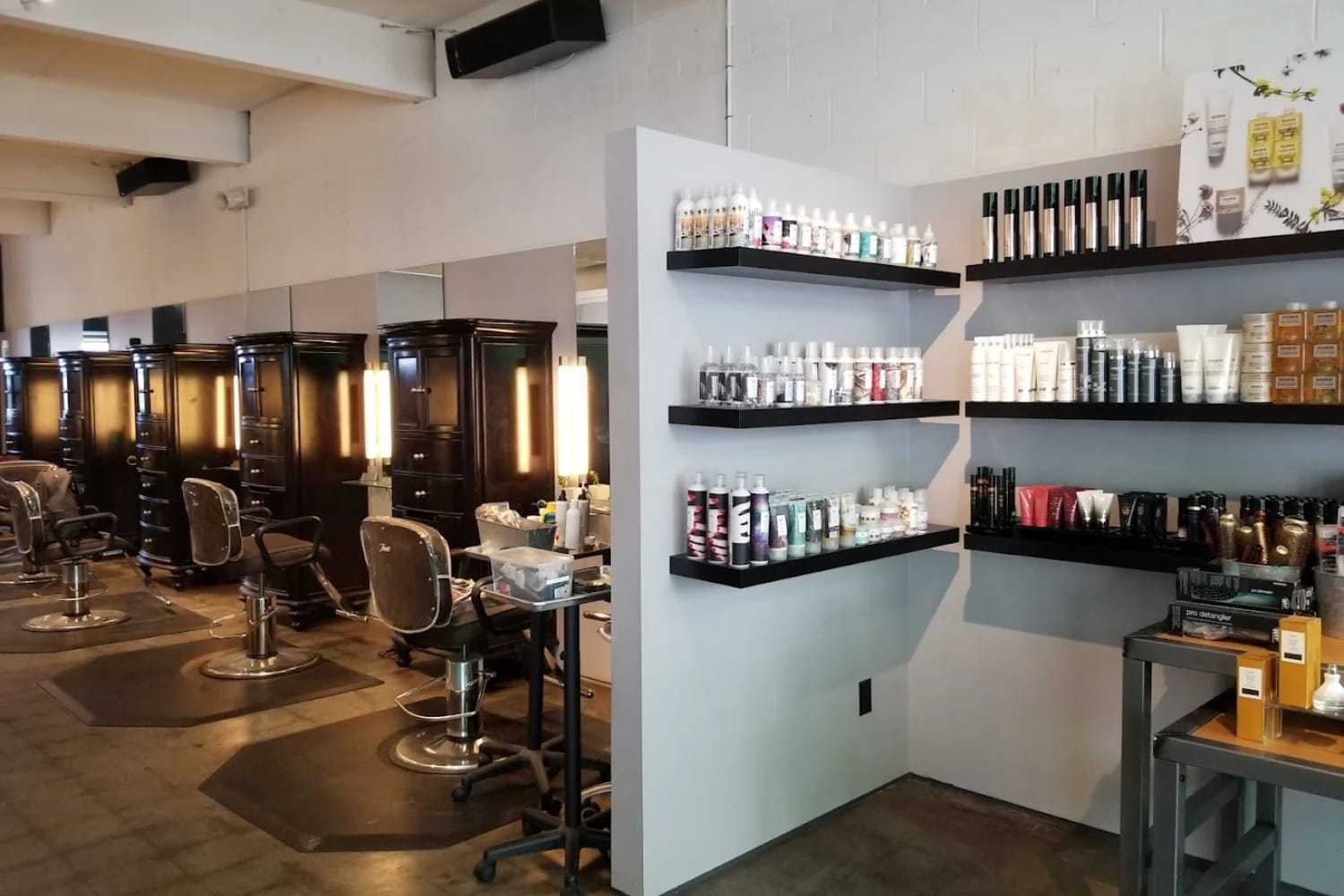 Modern salon interior with styling chairs, mirrors, and shelves of hair products.